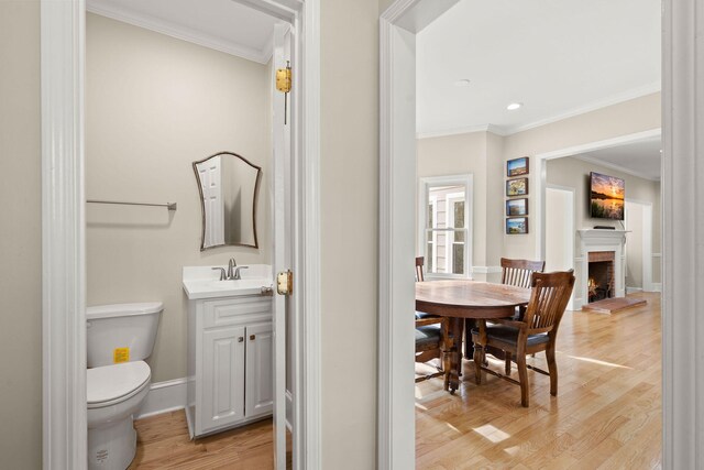 bathroom with wood-type flooring, vanity, crown molding, and toilet