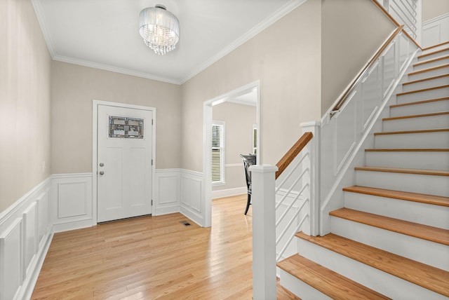 entrance foyer featuring crown molding, light hardwood / wood-style flooring, and an inviting chandelier