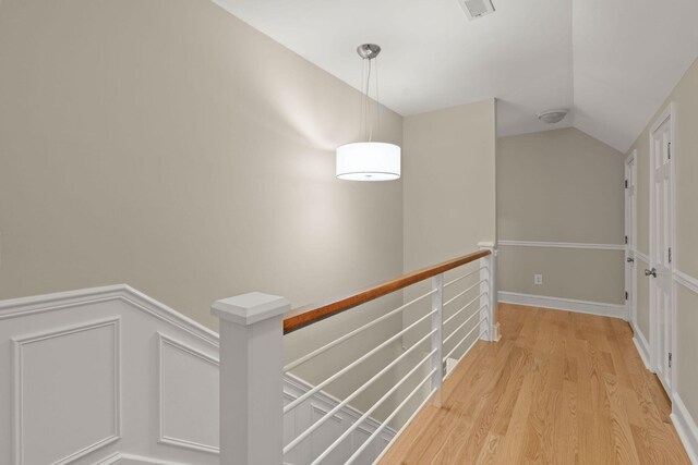 hallway with light hardwood / wood-style floors and lofted ceiling