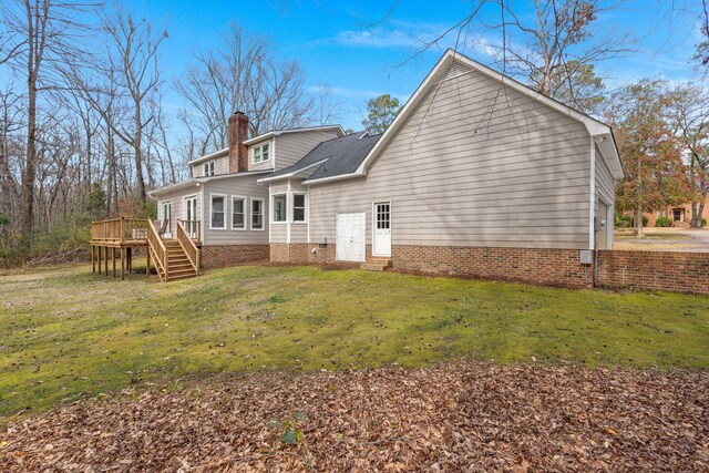 back of property featuring a wooden deck and a lawn