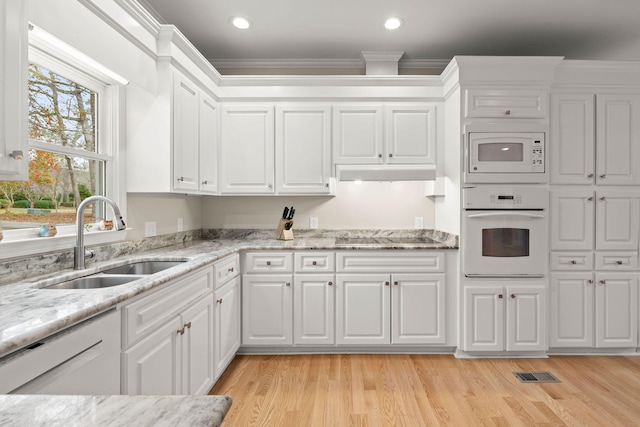 kitchen featuring sink, white appliances, light hardwood / wood-style floors, and white cabinetry