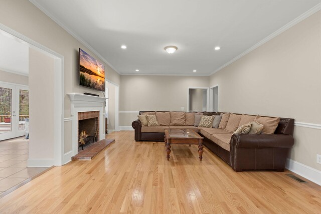 living room featuring a fireplace, light wood-type flooring, and ornamental molding