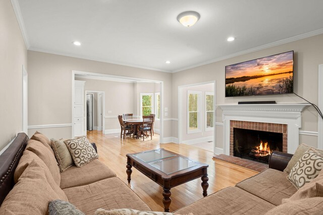 living room featuring a fireplace, light hardwood / wood-style flooring, and ornamental molding