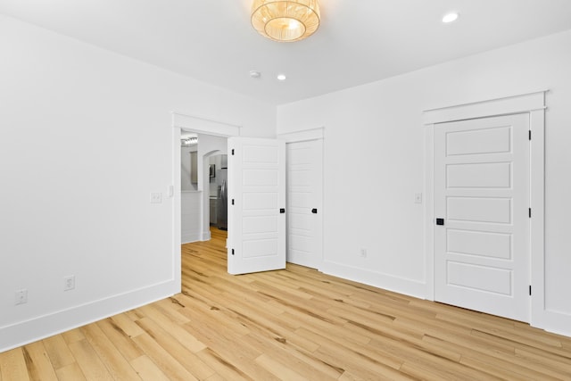 unfurnished bedroom featuring light hardwood / wood-style flooring and stainless steel refrigerator with ice dispenser