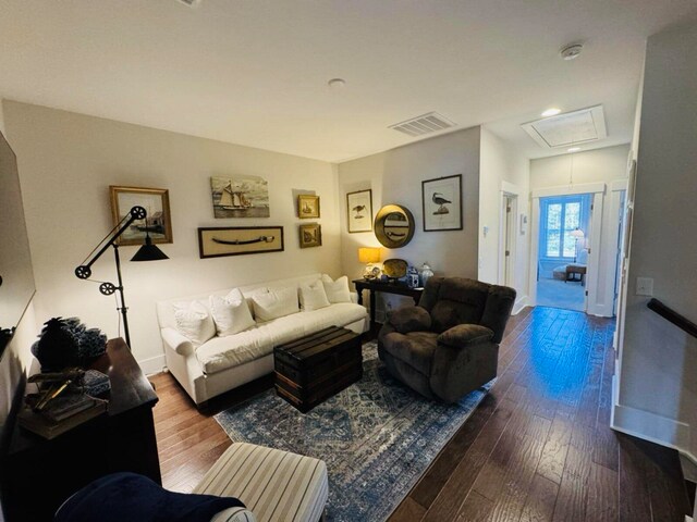 living room with visible vents, baseboards, attic access, and hardwood / wood-style flooring