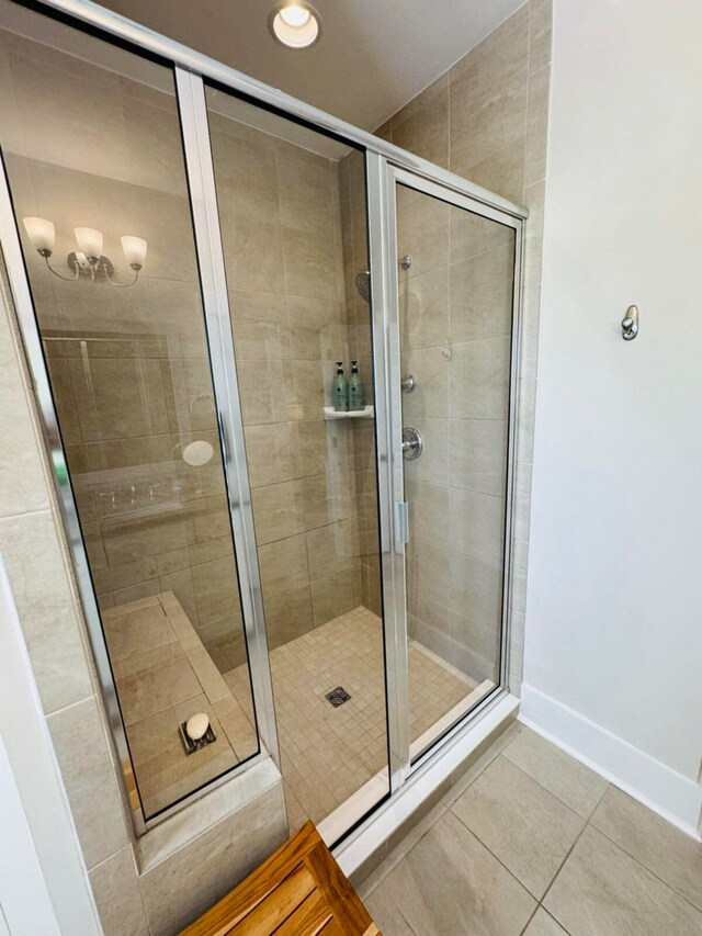 full bathroom featuring tile patterned floors, baseboards, and a shower stall