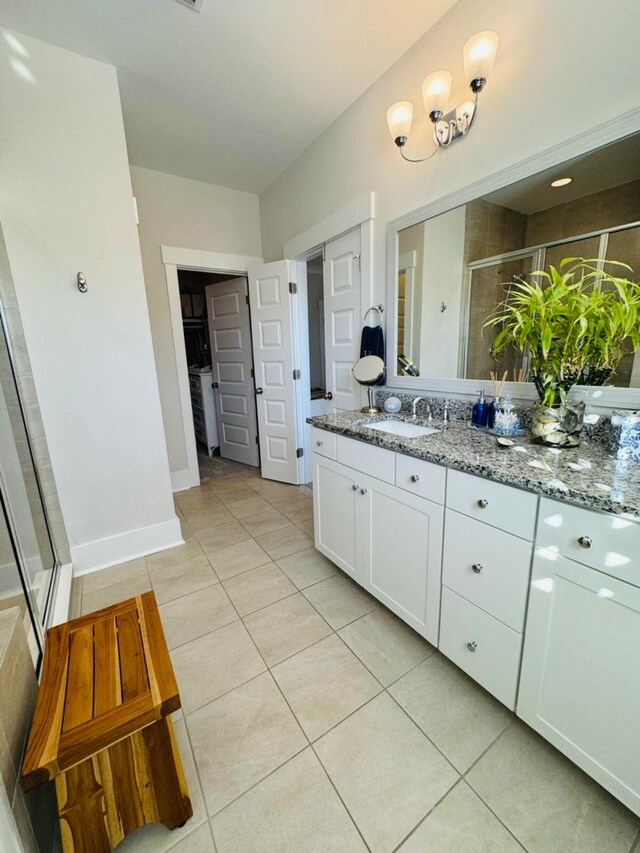 full bathroom featuring tile patterned flooring, a stall shower, vanity, and baseboards