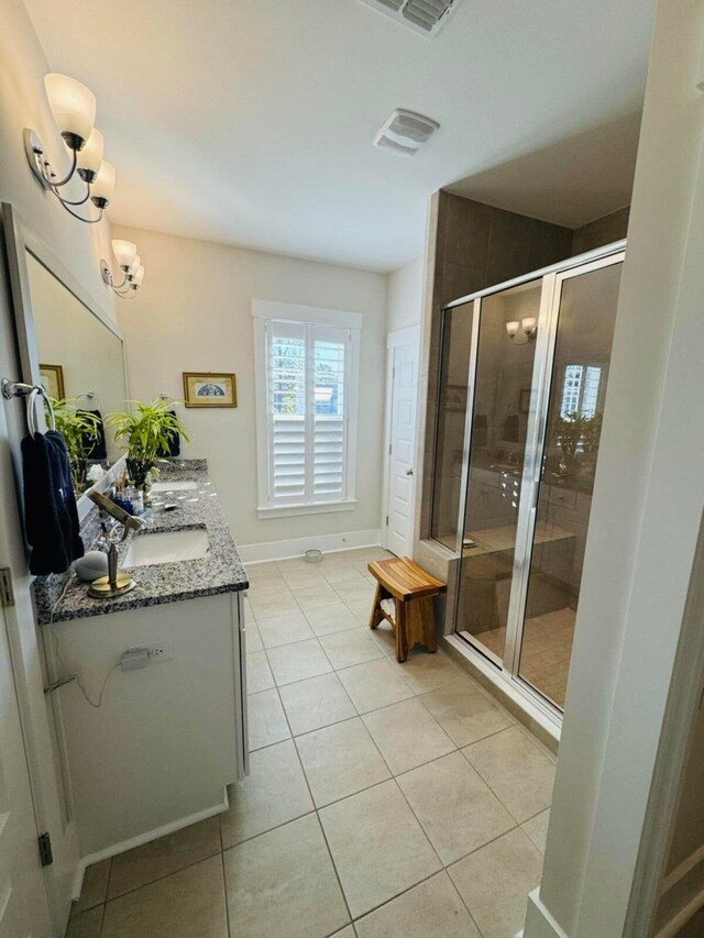 bathroom with tile patterned floors, a stall shower, a sink, double vanity, and baseboards