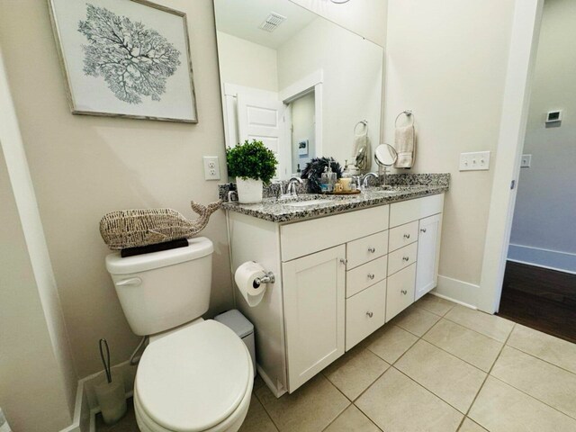 full bath featuring baseboards, double vanity, a sink, tile patterned floors, and toilet