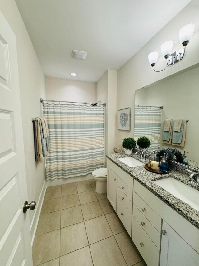 full bathroom with a sink, toilet, double vanity, and tile patterned floors