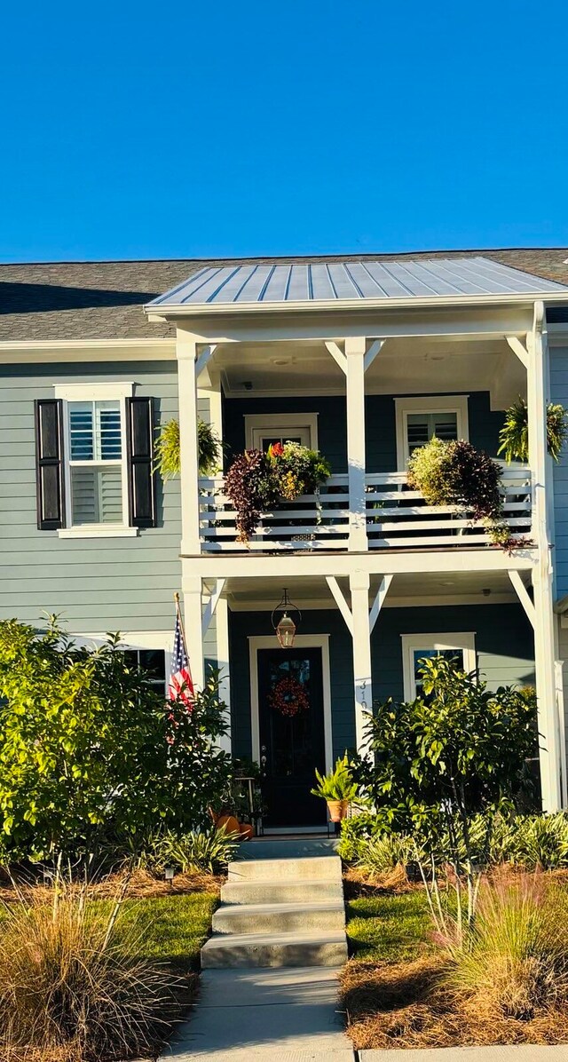 view of front of home with metal roof, a balcony, and a standing seam roof