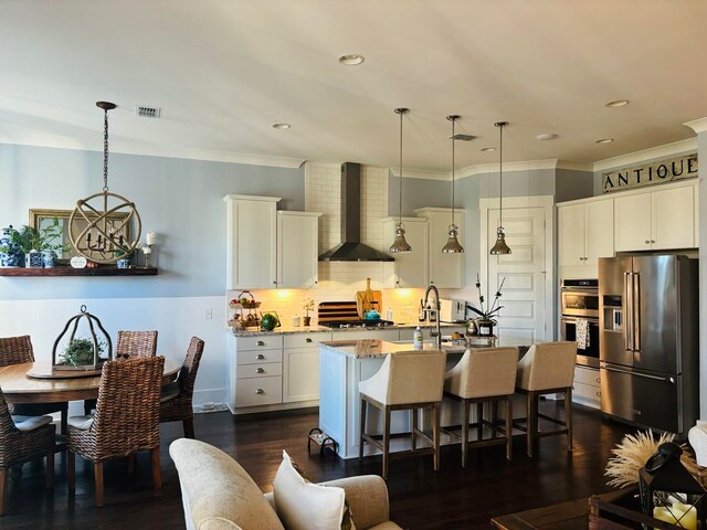 kitchen featuring light stone counters, appliances with stainless steel finishes, pendant lighting, a kitchen breakfast bar, and wall chimney exhaust hood