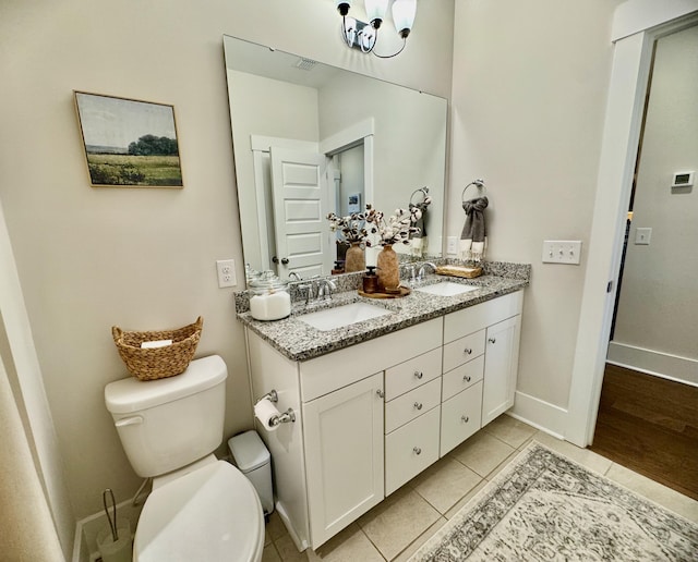 bathroom featuring tile patterned flooring, double vanity, toilet, and a sink