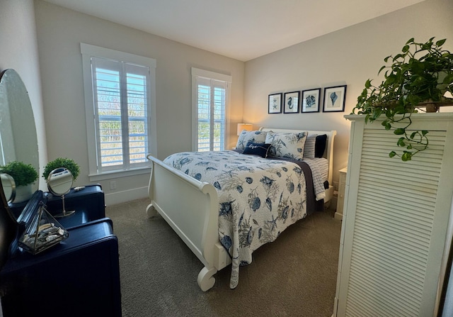 bedroom with dark colored carpet and baseboards