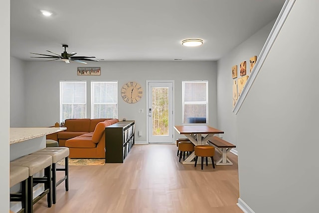 living room with light wood-style floors, baseboards, and a ceiling fan