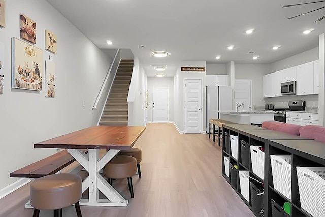 dining room featuring light wood-style floors, baseboards, stairway, and recessed lighting