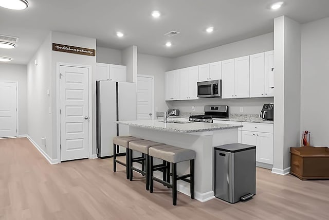 kitchen featuring white cabinetry, visible vents, stainless steel appliances, and a kitchen breakfast bar