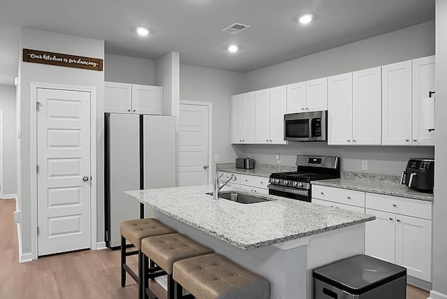 kitchen with appliances with stainless steel finishes, white cabinets, and a sink