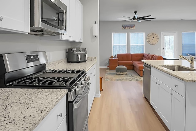 kitchen with appliances with stainless steel finishes, a sink, light wood-style floors, and white cabinets