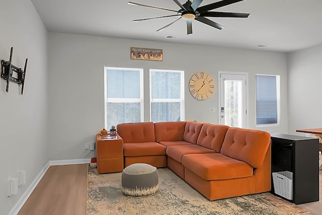 living room featuring a ceiling fan, visible vents, light wood-style flooring, and baseboards