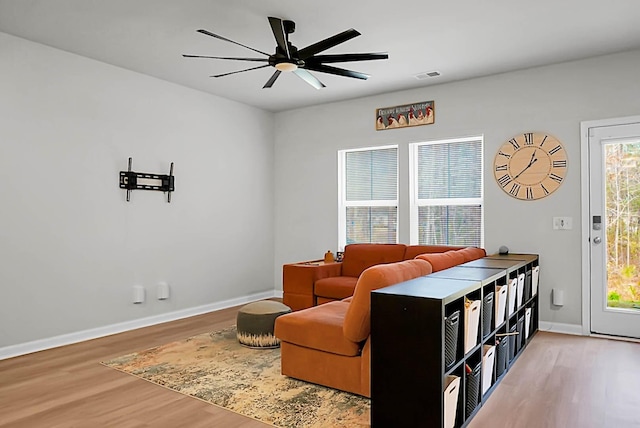 living area with ceiling fan, light wood-style flooring, visible vents, and baseboards