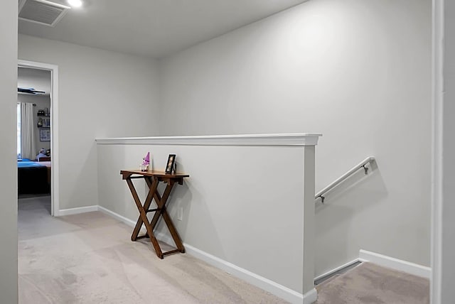 hall featuring visible vents, carpet floors, an upstairs landing, and baseboards