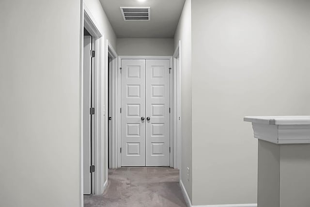 corridor featuring carpet flooring, visible vents, and baseboards