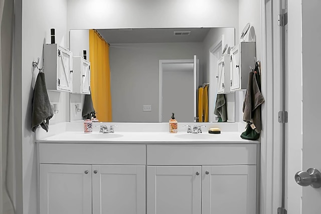 bathroom with double vanity, visible vents, and a sink