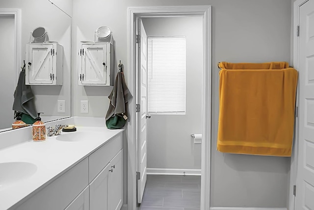 bathroom featuring double vanity, baseboards, and a sink