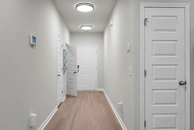 corridor featuring light wood-style floors and baseboards