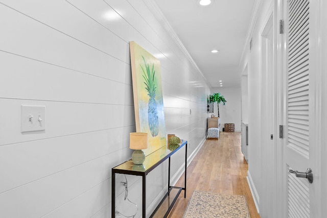 corridor with light hardwood / wood-style floors and crown molding