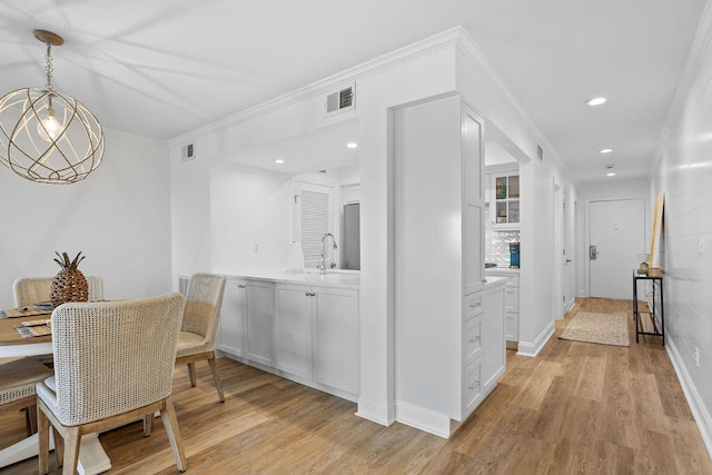 interior space featuring sink, an inviting chandelier, light hardwood / wood-style floors, and ornamental molding