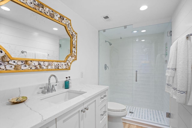 bathroom with hardwood / wood-style floors, vanity, toilet, and a shower with door