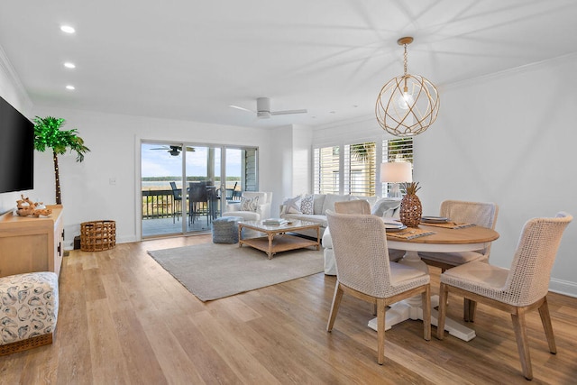 dining room with crown molding, plenty of natural light, ceiling fan with notable chandelier, and light wood-type flooring