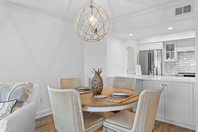 dining area with dark hardwood / wood-style floors, ornamental molding, and an inviting chandelier