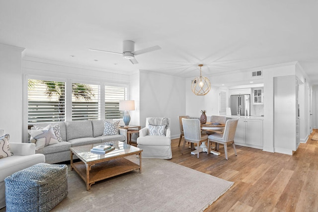 living room featuring crown molding, light hardwood / wood-style flooring, and ceiling fan