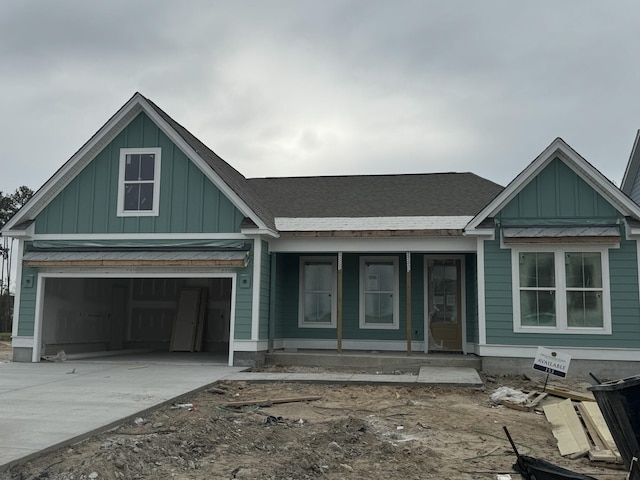 view of front of house with concrete driveway, a porch, board and batten siding, and roof with shingles