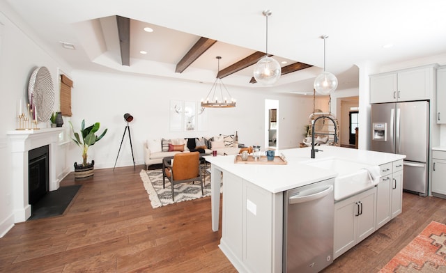 kitchen featuring a glass covered fireplace, appliances with stainless steel finishes, open floor plan, wood finished floors, and a sink