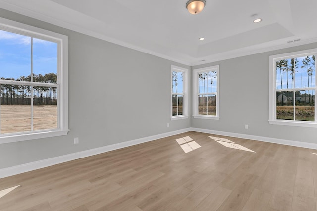 empty room featuring a healthy amount of sunlight, light wood-style floors, baseboards, and visible vents