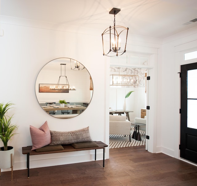 foyer entrance featuring crown molding, visible vents, an inviting chandelier, wood finished floors, and baseboards