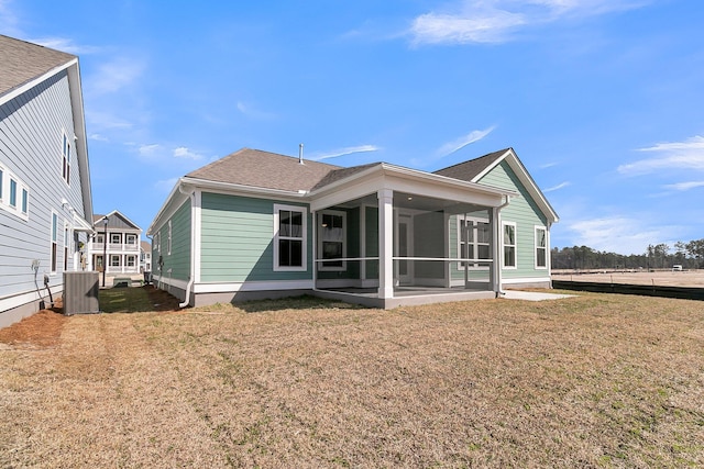 rear view of house featuring a yard, roof with shingles, a sunroom, and central air condition unit