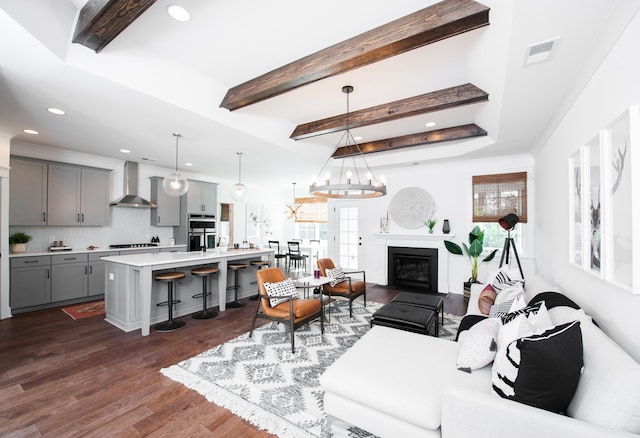 living area with beam ceiling, dark wood-style flooring, visible vents, and a healthy amount of sunlight