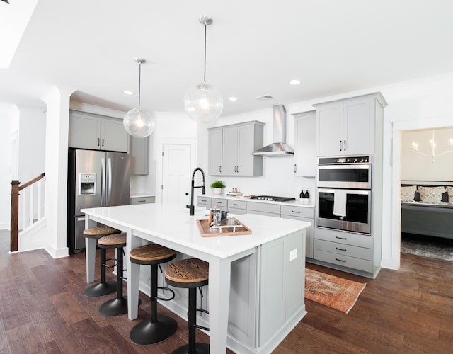 kitchen featuring wall chimney exhaust hood, appliances with stainless steel finishes, and gray cabinets