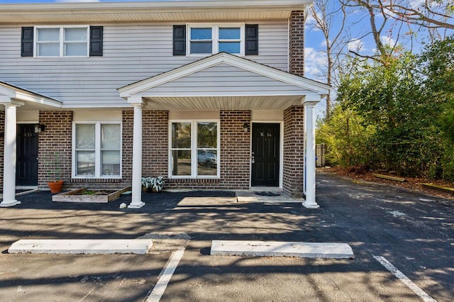 view of front facade with uncovered parking and brick siding