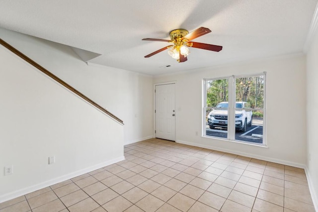 unfurnished room with ceiling fan, light tile patterned floors, baseboards, and ornamental molding