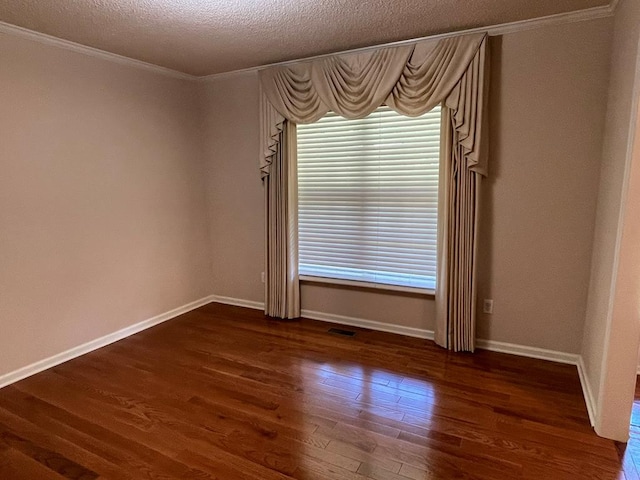 unfurnished room featuring dark wood-type flooring, ornamental molding, and a textured ceiling