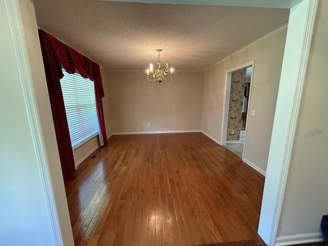 unfurnished dining area featuring ornamental molding, hardwood / wood-style flooring, an inviting chandelier, and a textured ceiling