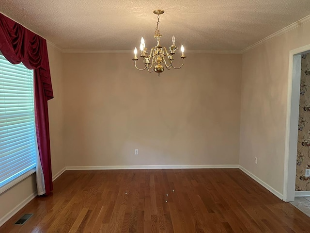 unfurnished room featuring ornamental molding, an inviting chandelier, hardwood / wood-style floors, and a textured ceiling