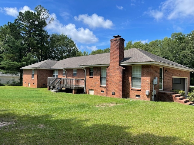 rear view of house with a garage, a deck, and a yard