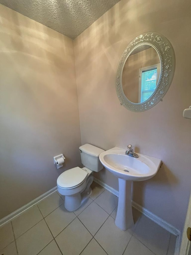 bathroom with a textured ceiling, toilet, and tile patterned floors